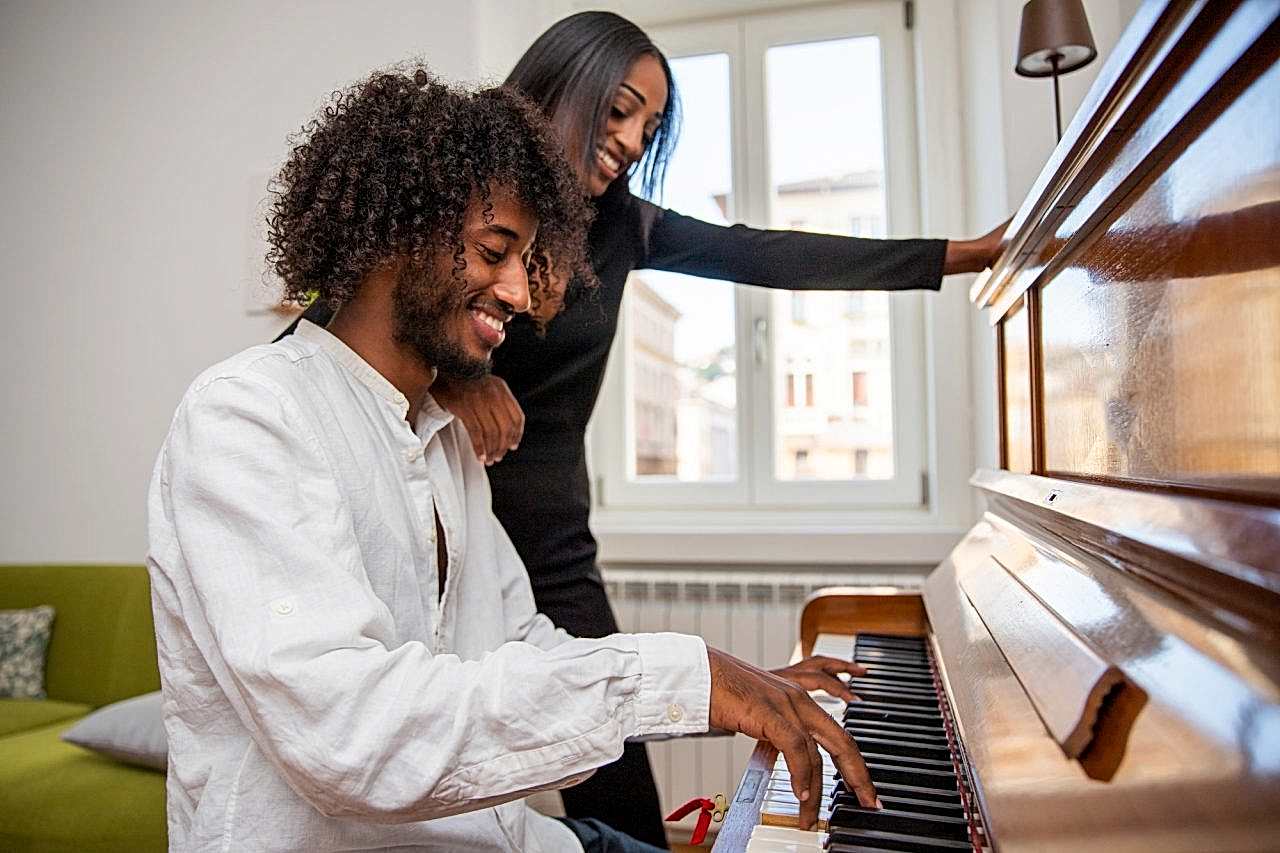 A boy plays a piano with his friend and they have fun, music class