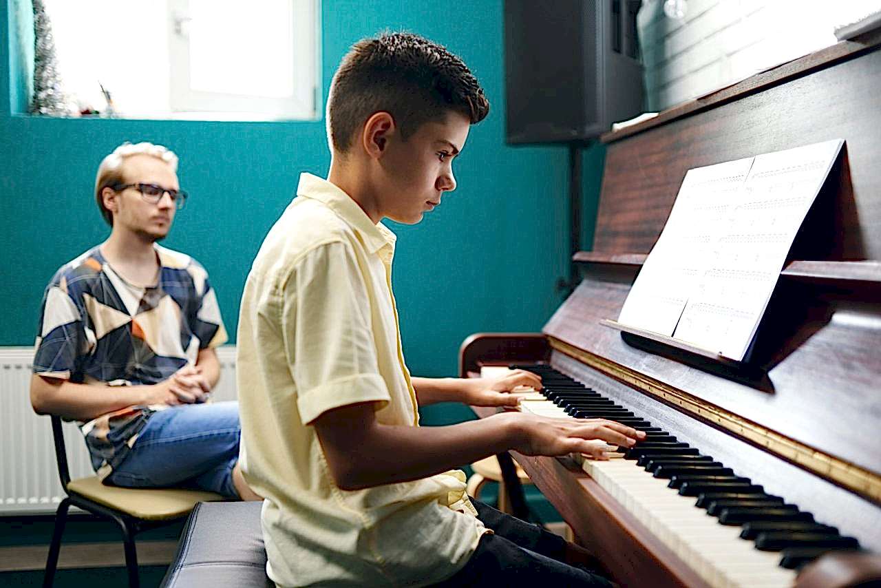 Piano teacher with a student playing the piano at lesson