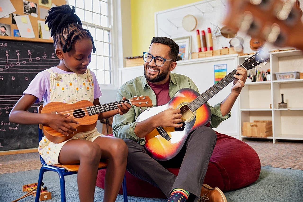 Teacher and students playing guitar together during music lesson